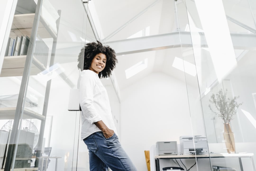 Portrait of smiling young woman in office. Benefits of skylight for commercial building