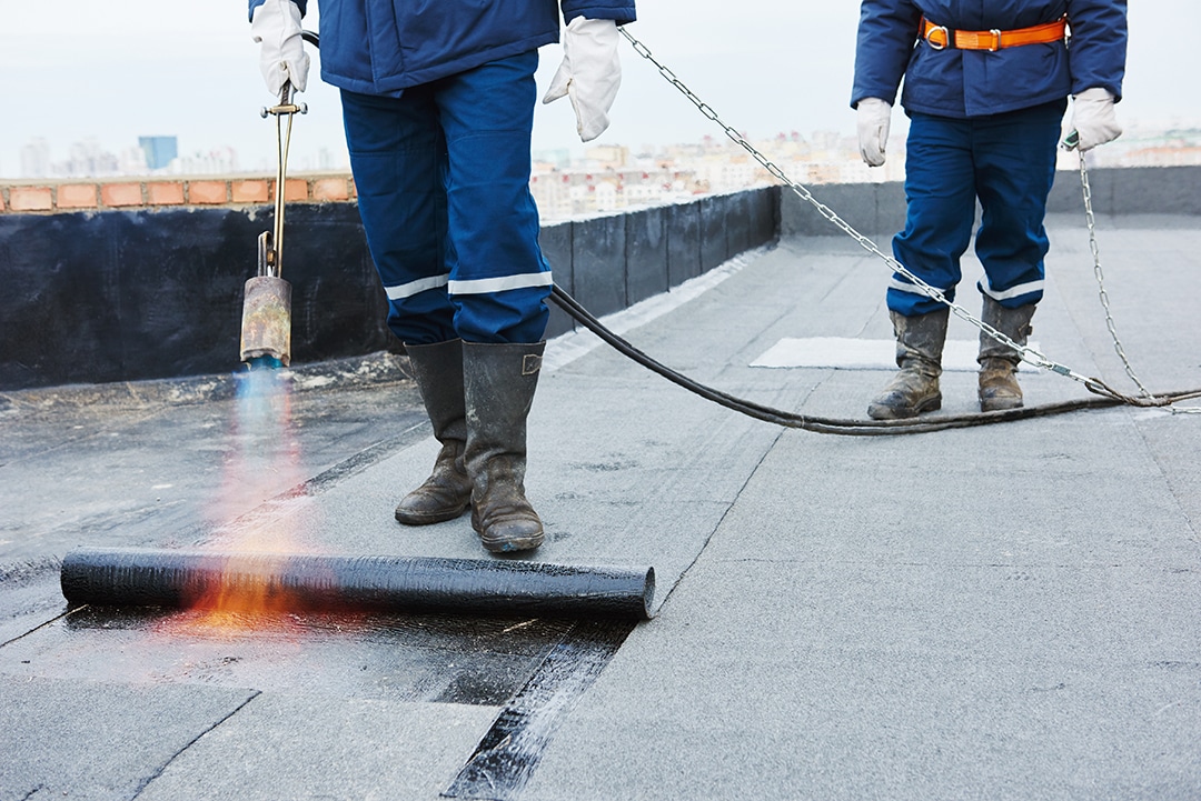 Flat roof installation. Heating and melting bitumen roofing felt